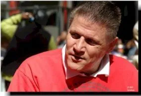 Picture of Mark Johnson A man with short dark hair and a red top looks off to the left of the picture
