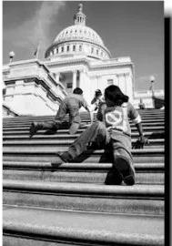 Black and white image showing people crawling and scooting up a large outdoor stairway in front of a government building. Event known as the Capitol Crawl.