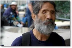 Picture of a man with a bushy grey and black beard, eyes closed facing the camera.