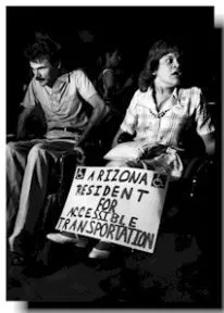 Black and white photo of a man and a woman in wheelchairs.  The woman looks off to the right of the frame and holds a sign that says "Arizona resident for accessible transportation".