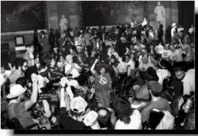 Black and white photo of a group of people in wheelchairs. Some have the power fist raised.