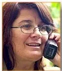 A woman with long dark hair and eyeglasses speaks into a wireless phone.
