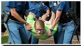 A man in a bright green top is carried by four police officers at a protest.