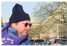 A man in a winter hat and sunglasses looks to the right of the image.