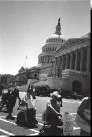ADAPT protestors marching in Washington D.C. Black and white photo of ADAPT protestors marching in the street. Government buildings are in the background.