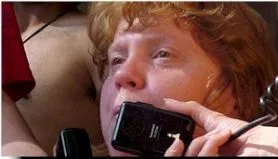 A close-up of a woman with read hair speaking on a telephone.