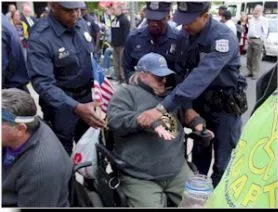 A person in a power wheelchair is being detained by three police officers.