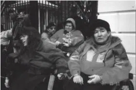 Black and white photo of a group of protestors outside of a gated entrance.