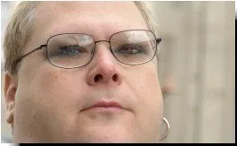 Person with blonde hair and glasses looks into the camera