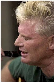 Picture of Johnny Crescendo A man with a short hair cut and green tee shirt has his eyes closed singing into a microphone.
