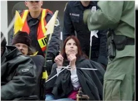 Picture of Dawn Russell A woman with dark hair holds up her wrists which are bound by plastic ties.