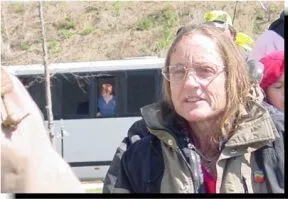Picture of a woman with long hair, glasses, and a dark jacket outside at an event.