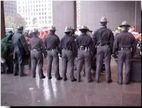 A picture of police officers, taken from behind, blocking off ADAPT protestors