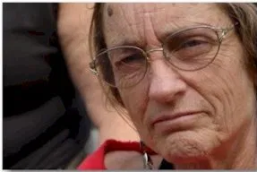 A person with glasses stares intently into the camera