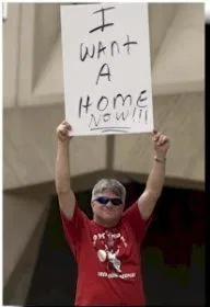 I want a home now! A person in a red top hold a sign over their head that says "I want a home now!!!"